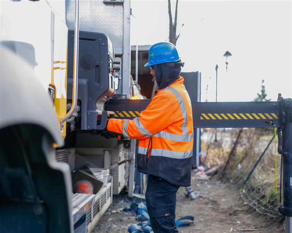 Employé Intermat en livraison sur un chantier, manipulant des équipements à partir d’un camion, illustrant le rôle d’un fournisseur de finition intérieure dans la gestion de chantier et la coordination des matériaux.